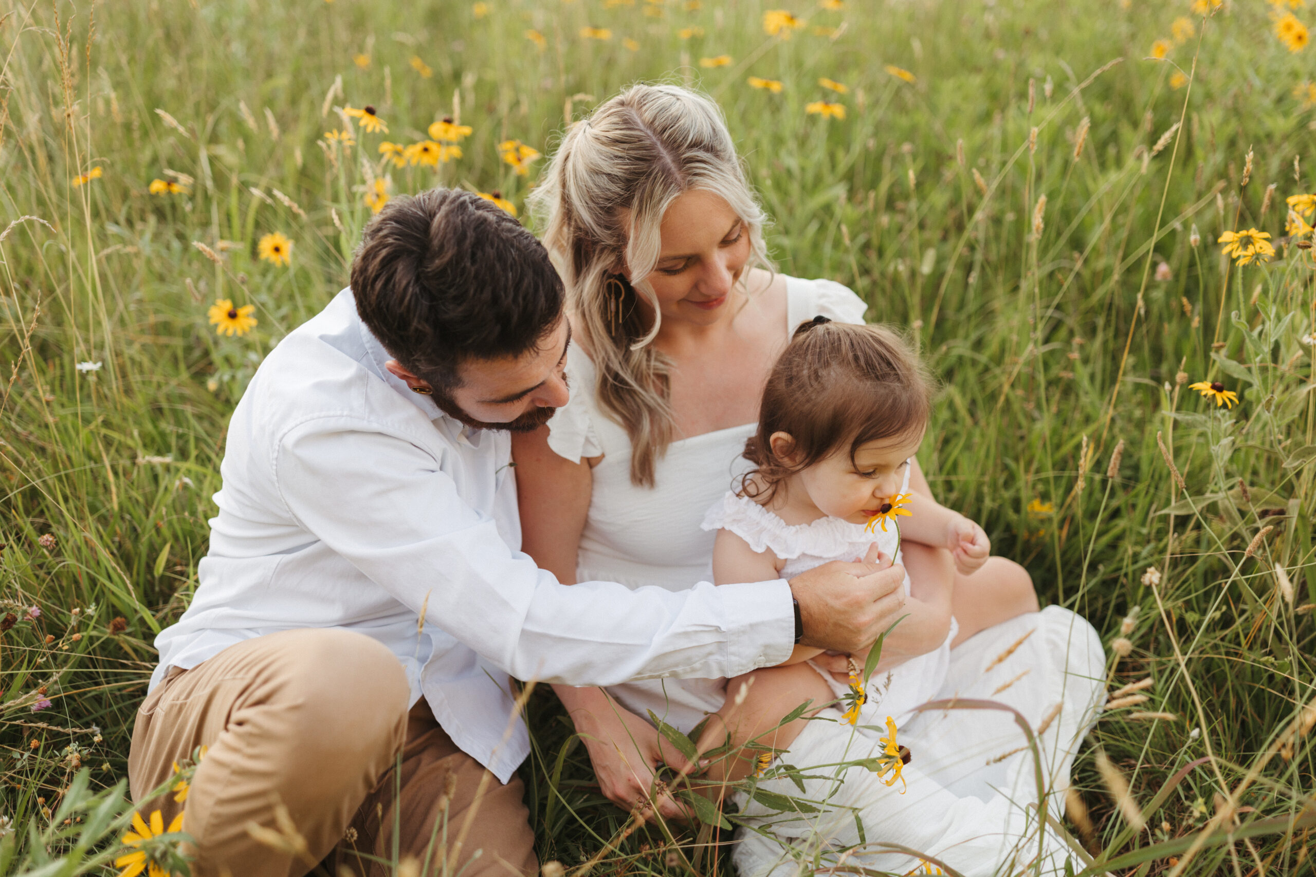 Family wearing white outfits sitting in a wildflower field