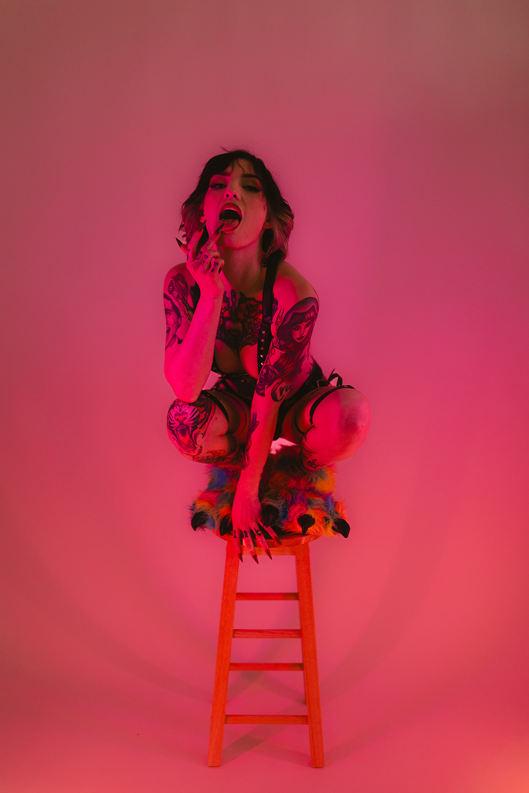 A woman perched on a stool for her boudoir photoshoot