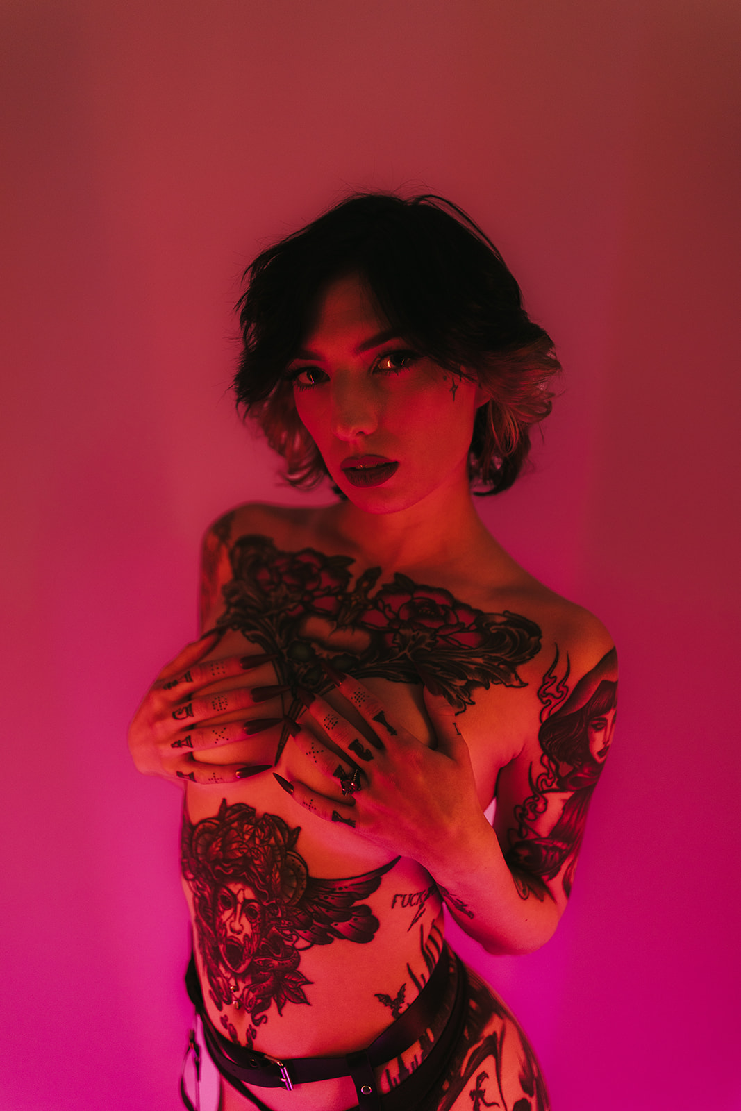 A girl posing for boudoir photos in pink and red lighting