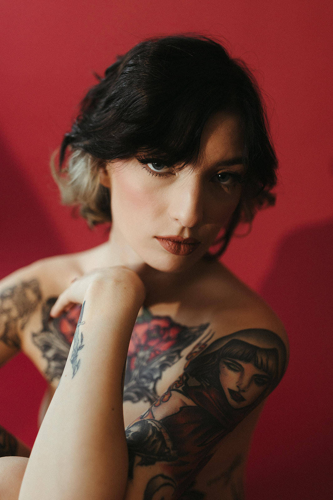 A girl looking at the camera during her boudoir photos with a red studio backdrop