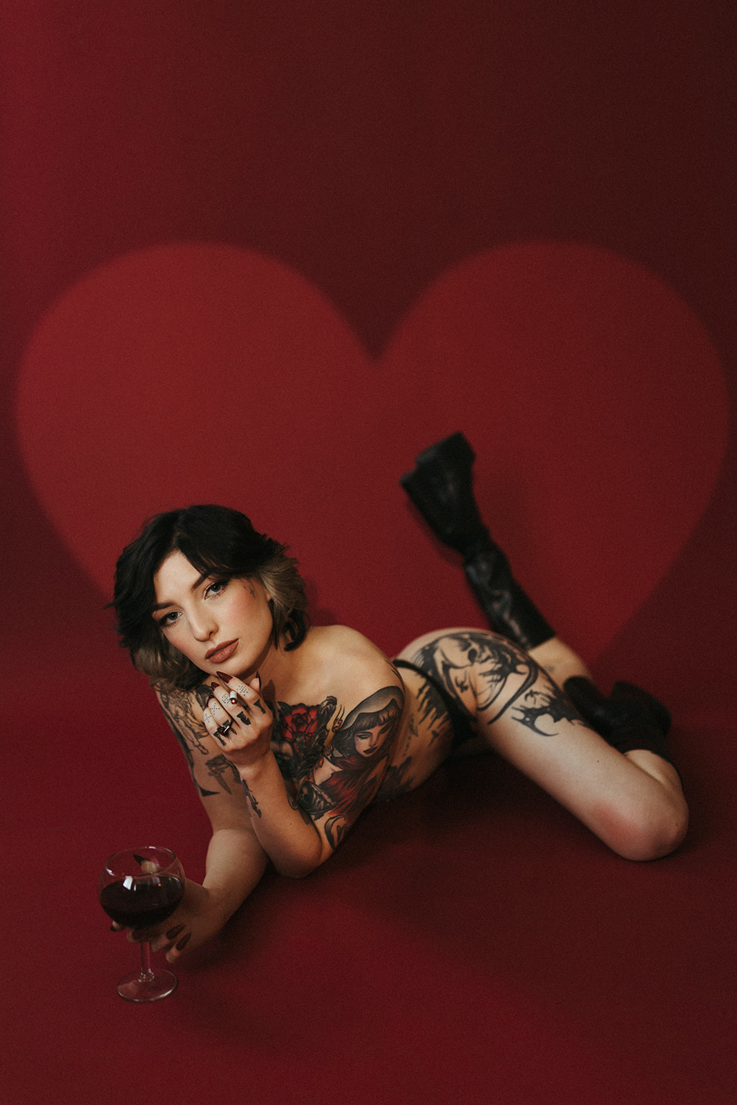 A girl laying on the ground with a cigarette and glass of wine for her boudoir photos