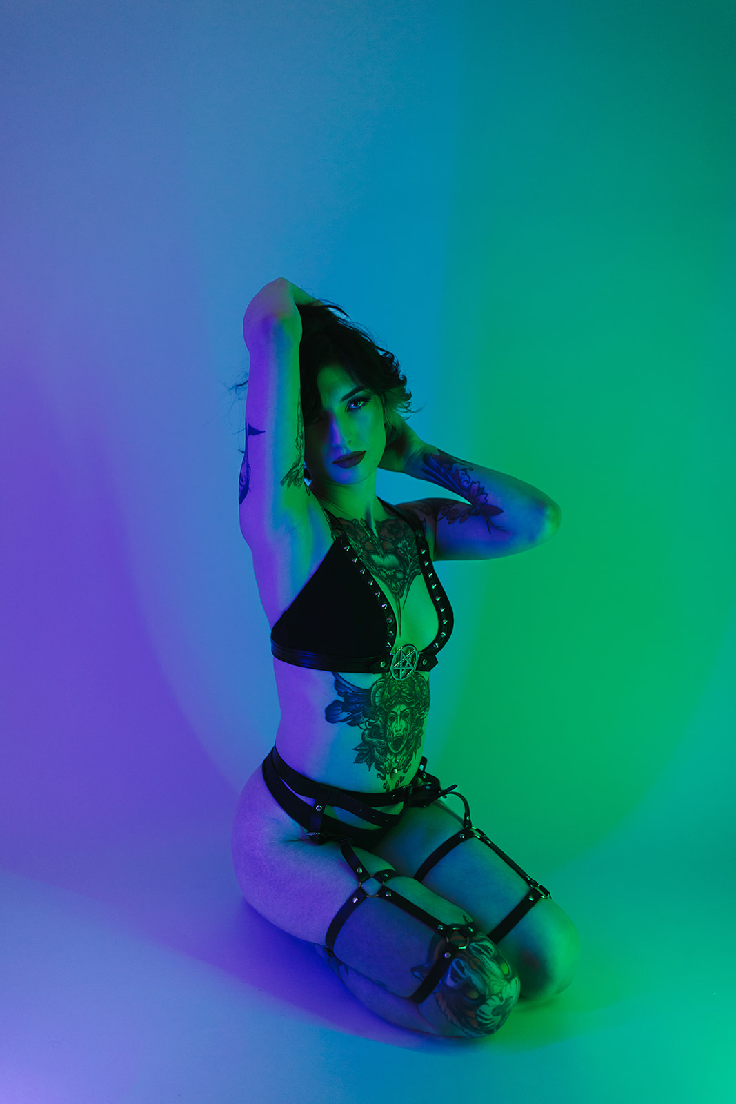 A girl sitting on the ground in blue and green lighting, perfect for boudoir photoshoot ideas