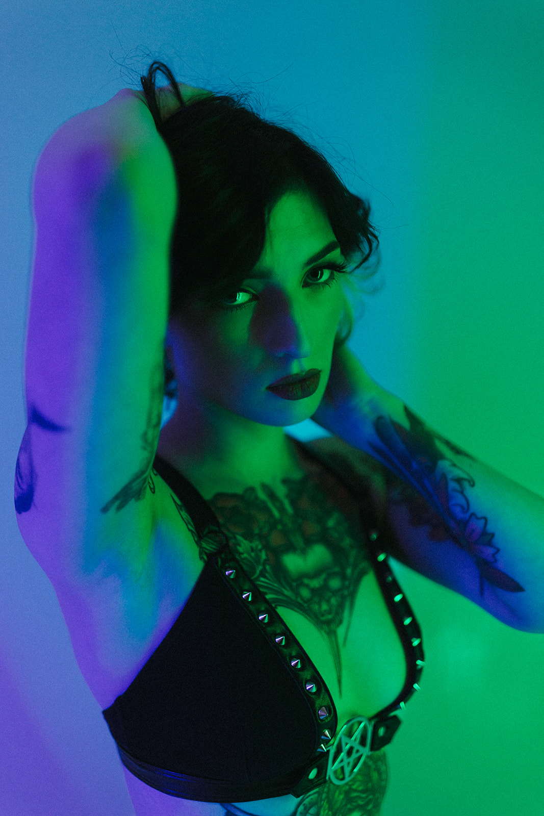 A woman looking at the camera for a boudoir photoshoot with blue and green lighting, as boudoir photoshoot ideas
