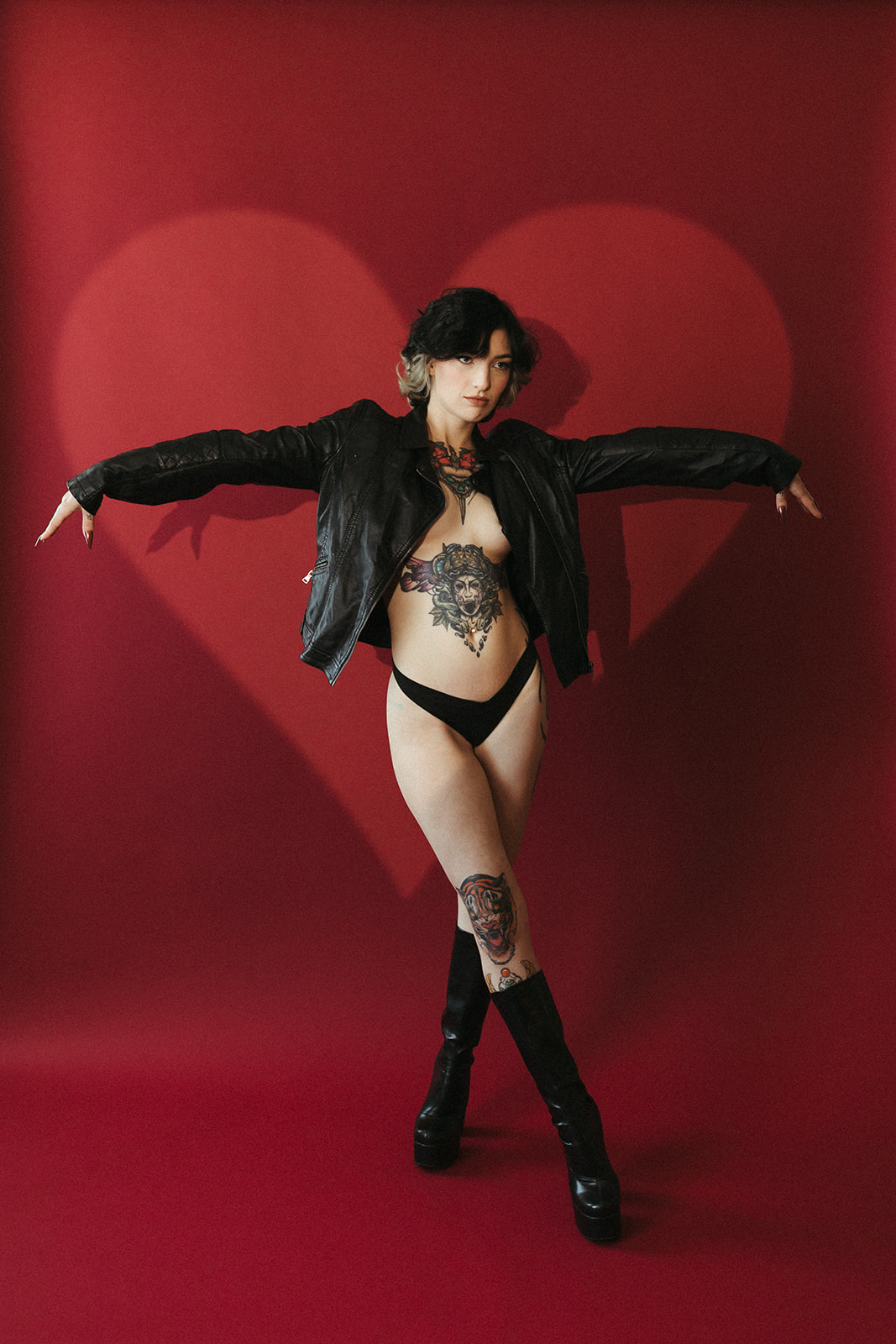 A girl posing for her boudoir photoshoot in a leather jacket and leather boots