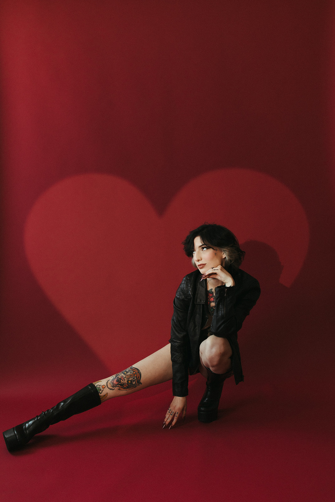 A boudoir photoshoot with a red backdrop and heart-shaped light background