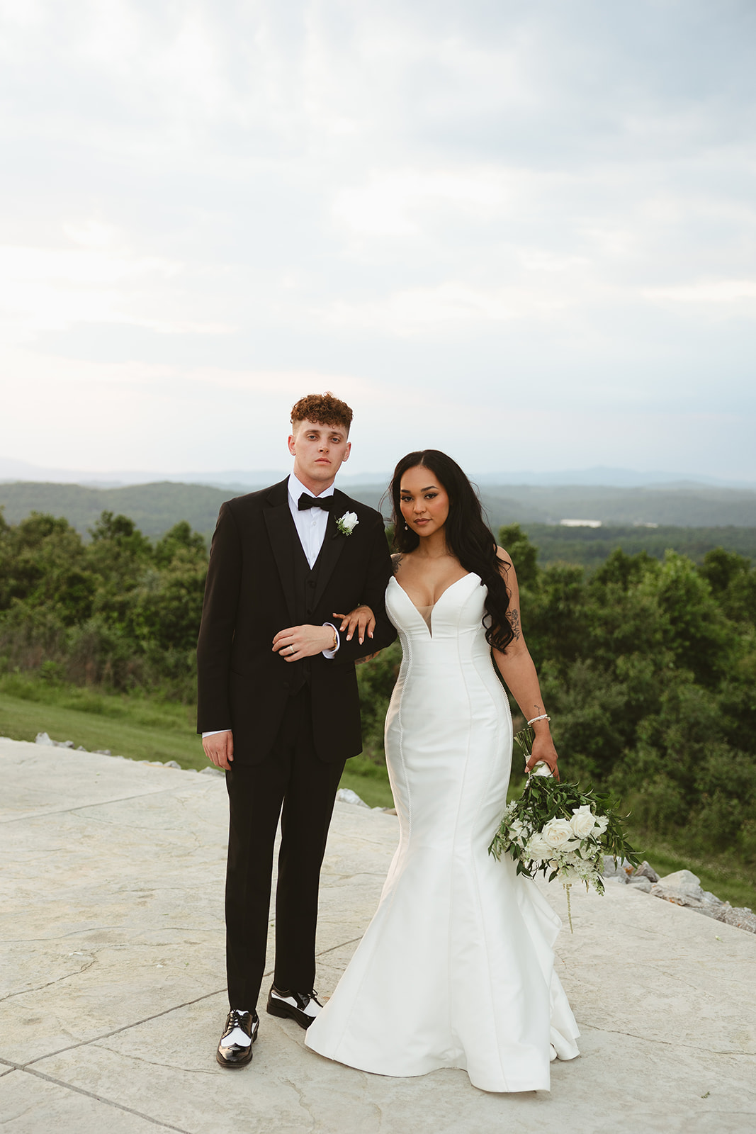 Bride and groom posing for wedding photos with mountain view venue