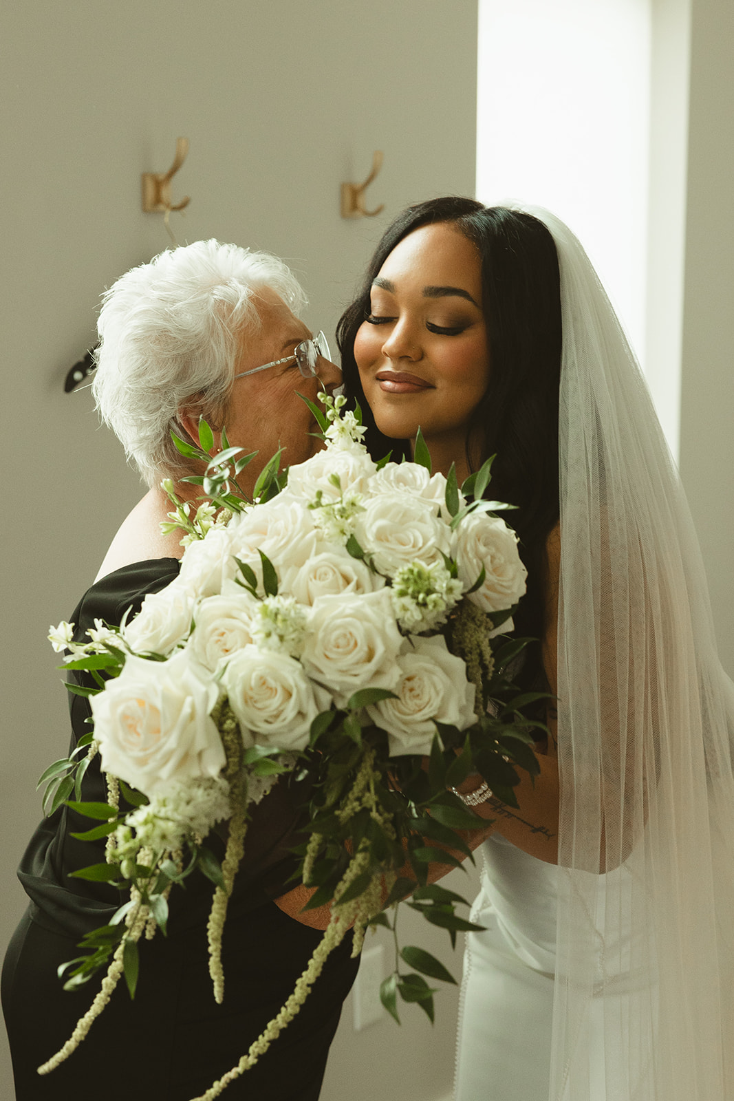 Bride's grandmother kissing her on the cheek during wedding getting ready photos