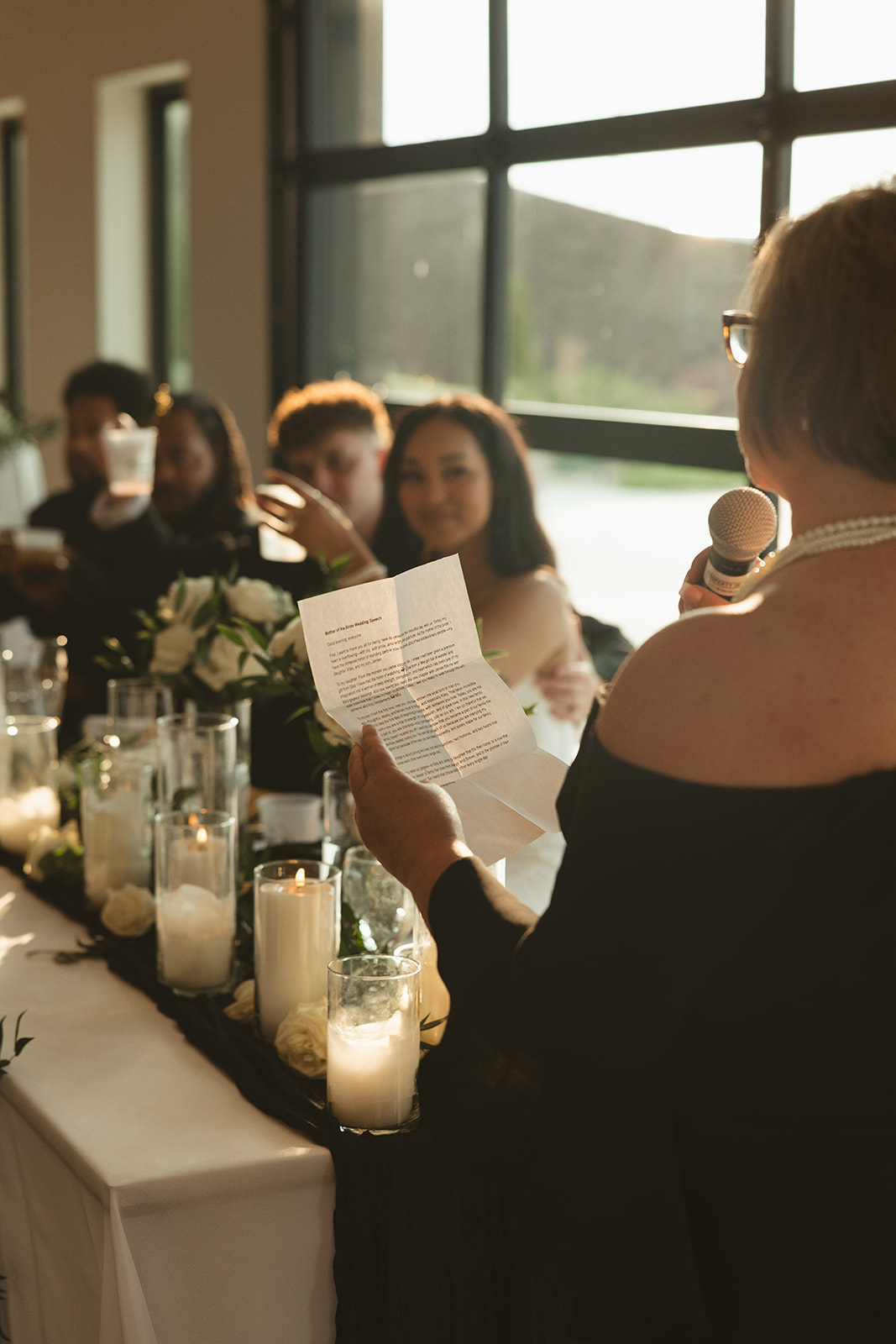 Candid wedding photo of bride's mother giving a toast at the wedding reception