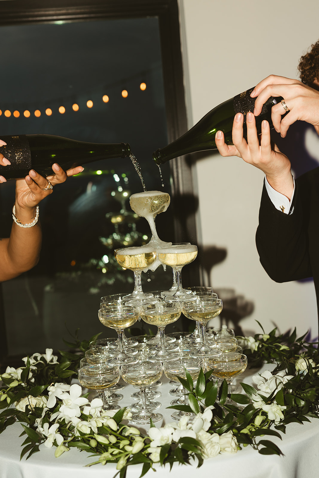 Bride and groom pouring champagne into a champagne tower at their wedding reception