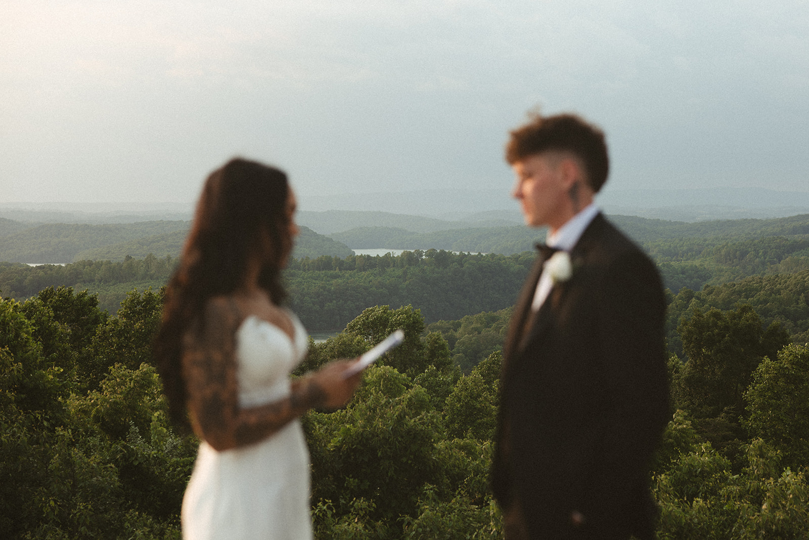 Editorial wedding photo of bride and groom reading private vows at sunset