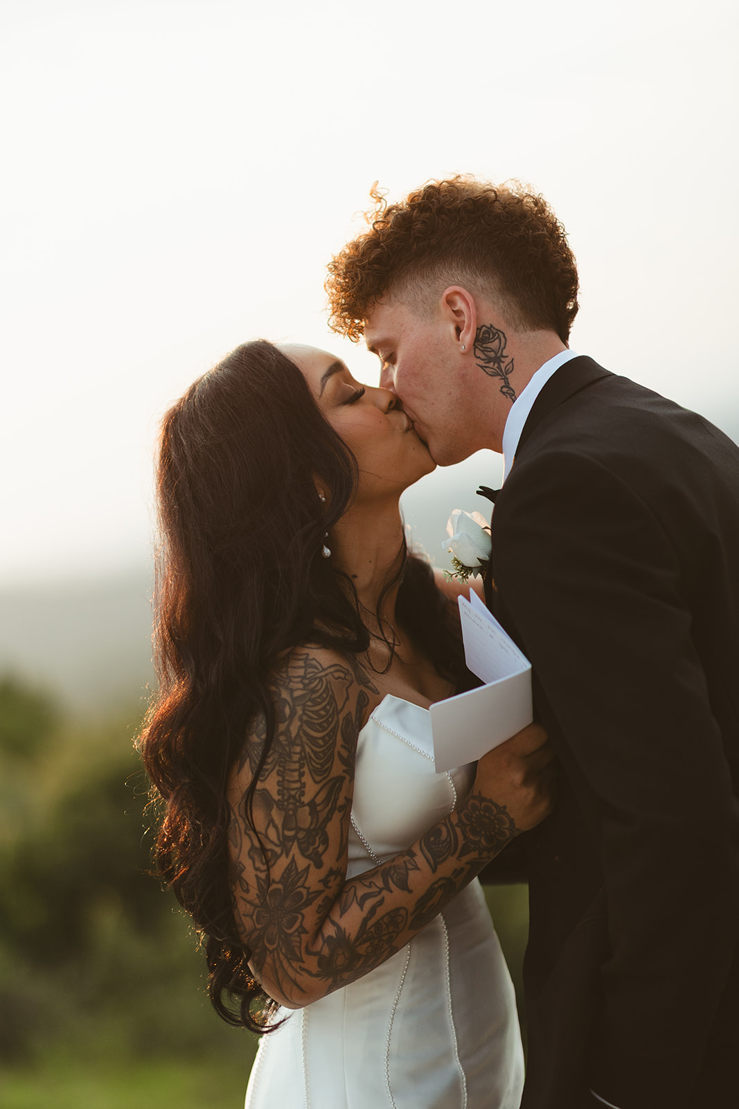 Bride and groom kissing during private vows at sunset