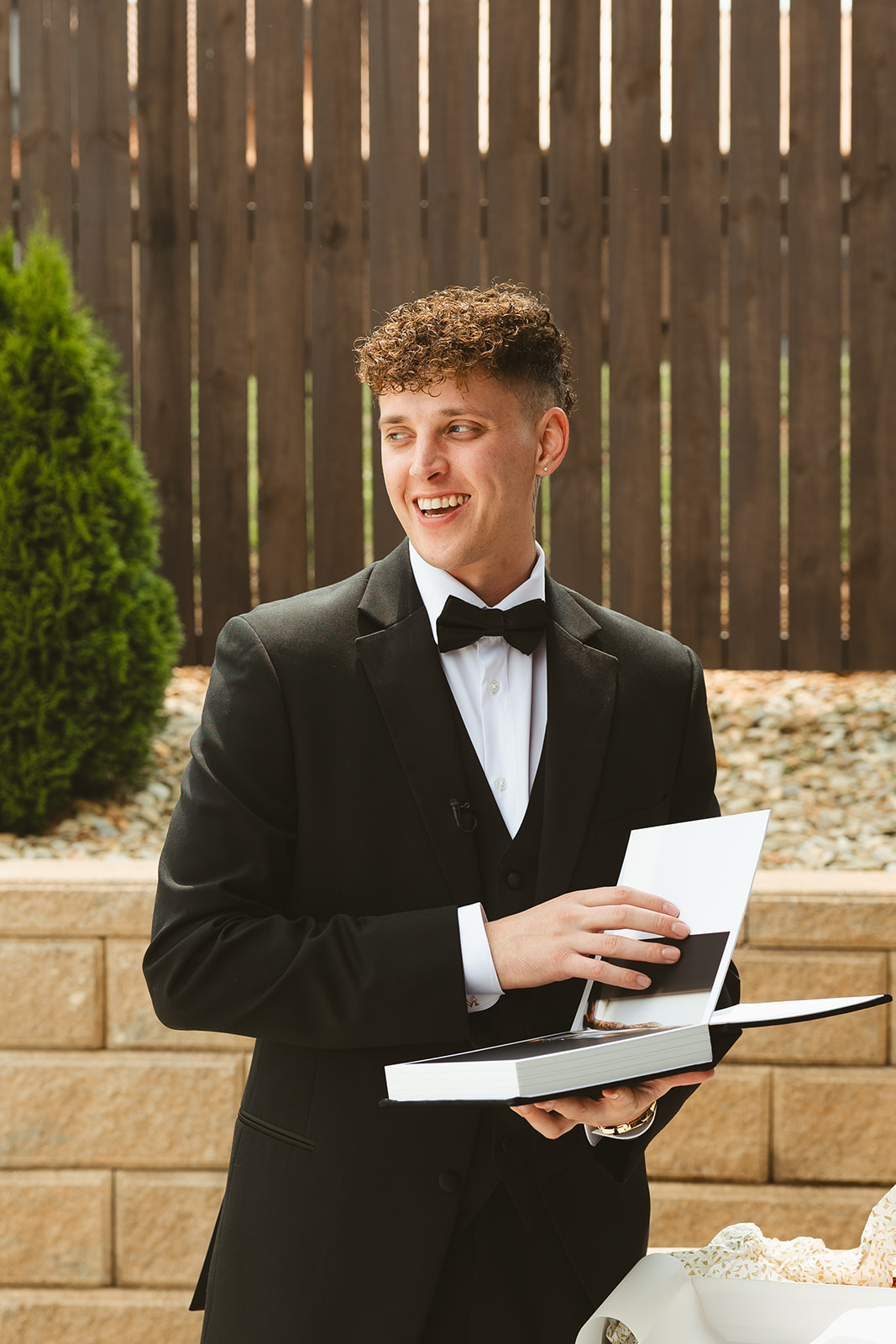 Groom laughing at bride's wedding gift to him: a book of her boudoir photos