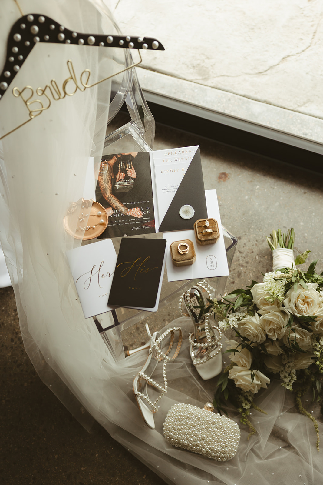 Black and white wedding details including a pearl veil, white wedding flowers, wedding shoes, wedding jewelry, wedding invitations, and vow books