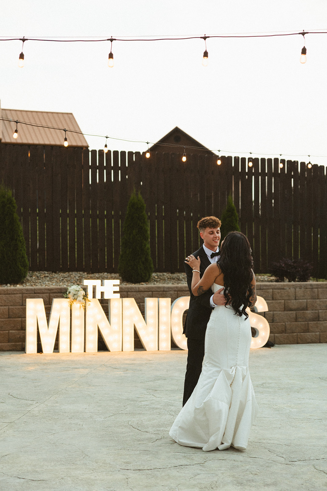 Bride and groom sharing first dance in front of large marquee letters