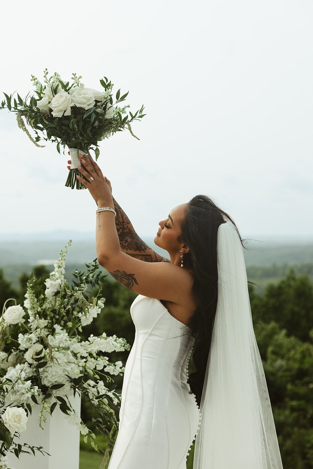 Bridal portrait of bride holding up her white wedding bouquet in the air