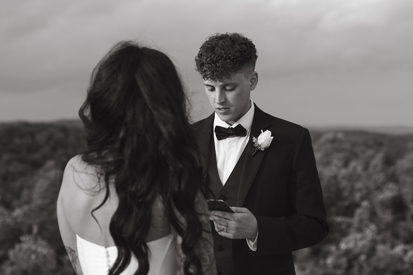 Black and white photo of groom reading private vows to bride
