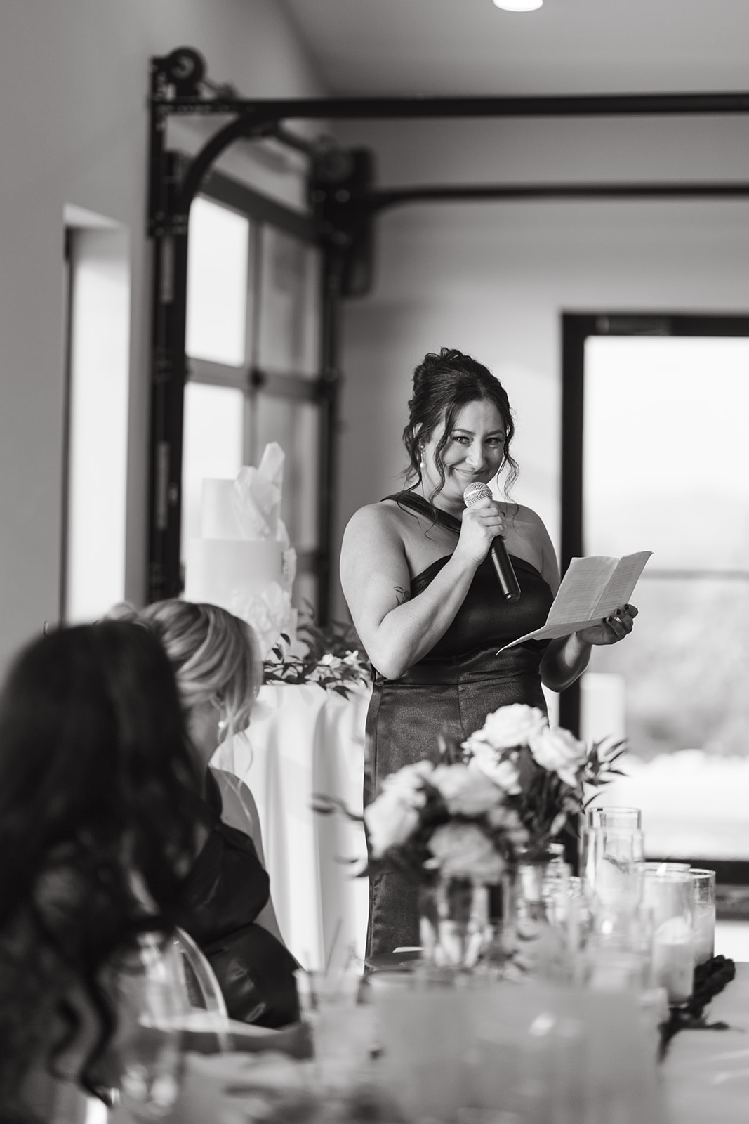 Candid wedding photo of bridesmaid giving a toast at wedding reception