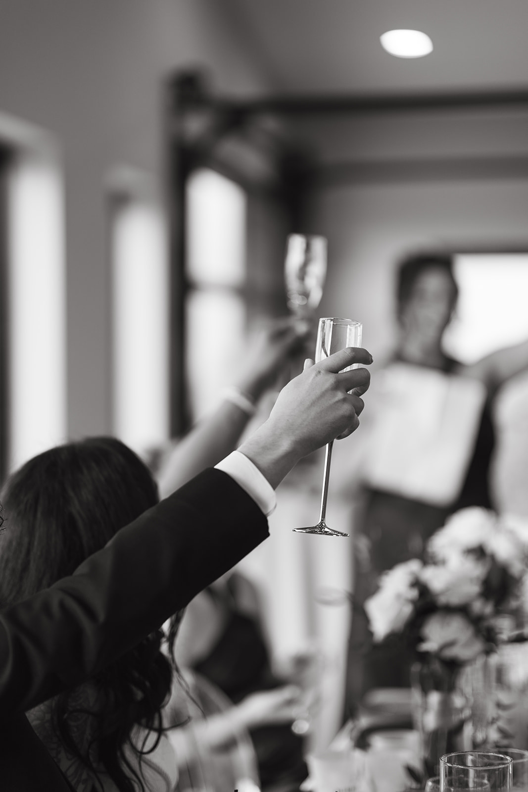 Candid wedding photo of guests raising their glass during wedding toasts