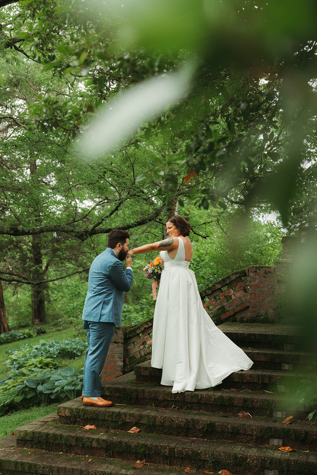 A man kissing his wife's hand during wedding photos, from a wedding full of colorful wedding ideas