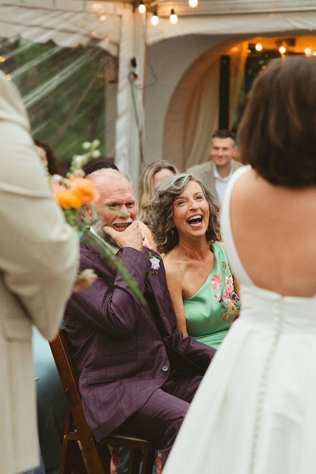 The bride's mom and dad laughing while watching the wedding ceremony