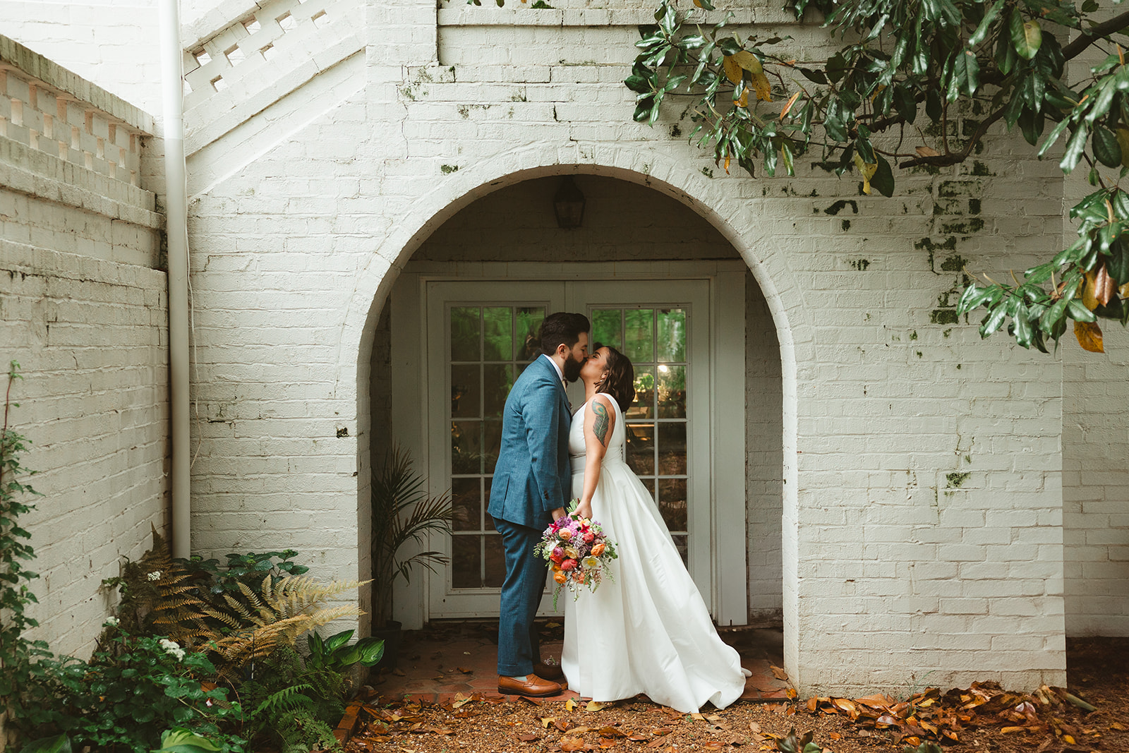 A bride and groom kissing underneath a wedding arch