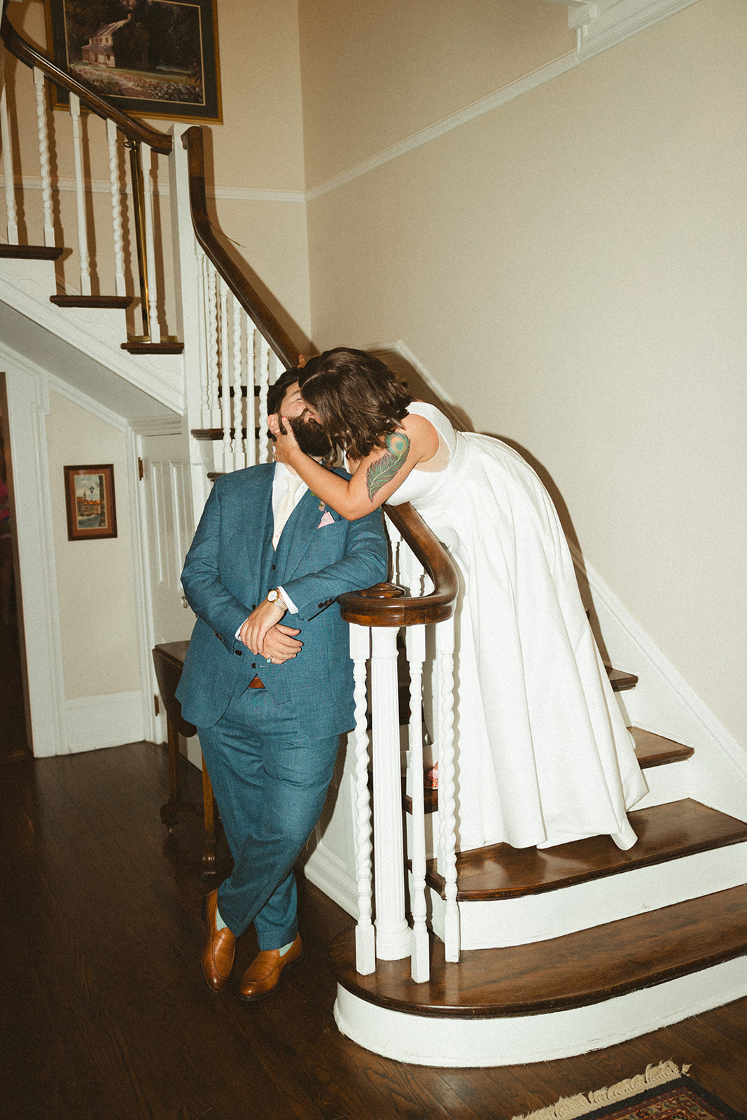 A bride kissing her husband on the staircase inside of their wedding venue, Maple Grove Estate