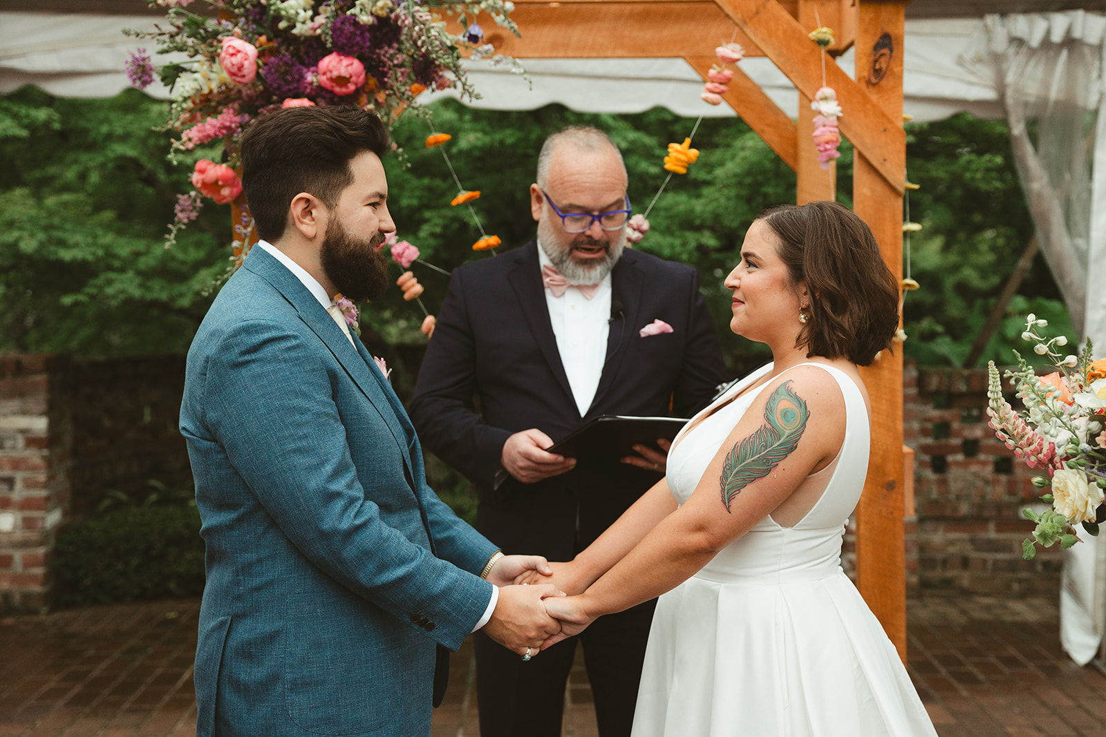 A couple holding hands at their colorful wedding ceremony at Maple Grove Estate