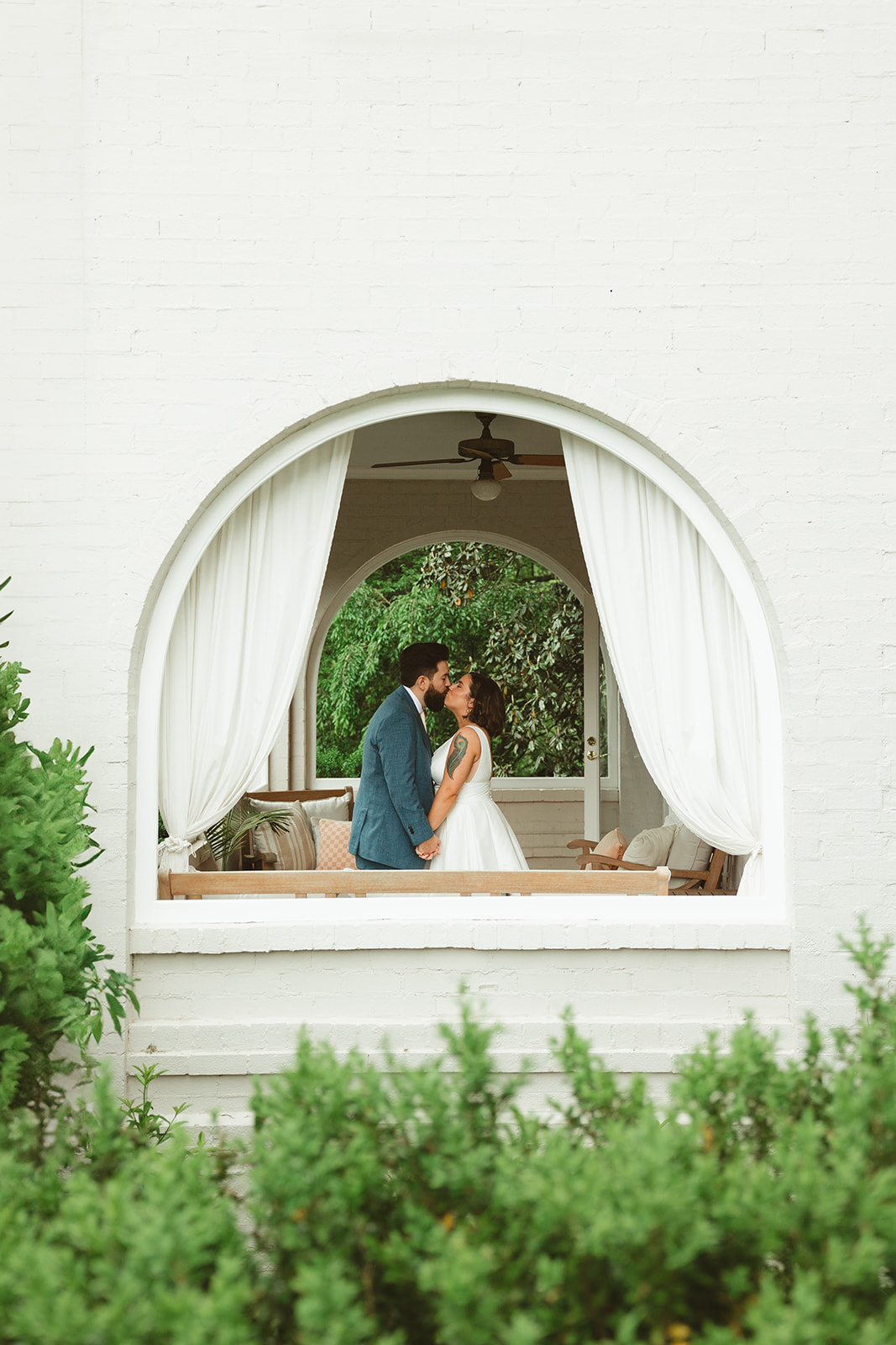 A couple kissing, as taken through an arched window at Maple Grove Estate