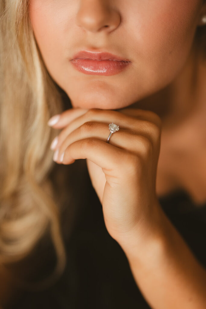 A woman with her hand on her chin showing off her engagement ring