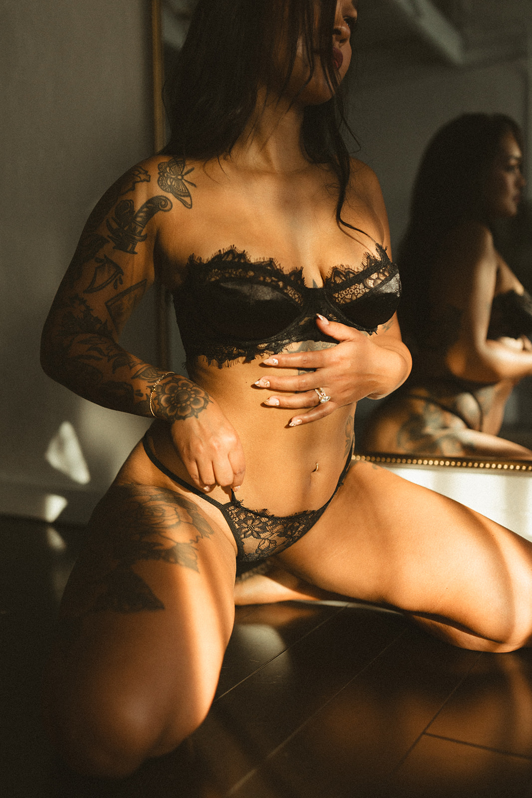 A woman posing for a boudoir shoot wearing black lace lingerie