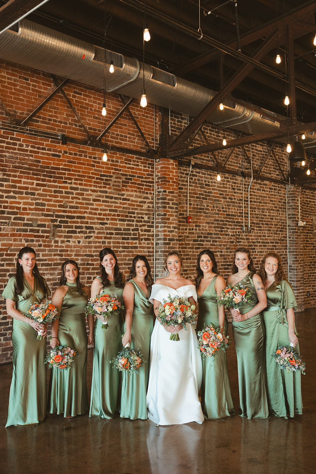 A bride and bridesmaids in green bridesmaid dresses