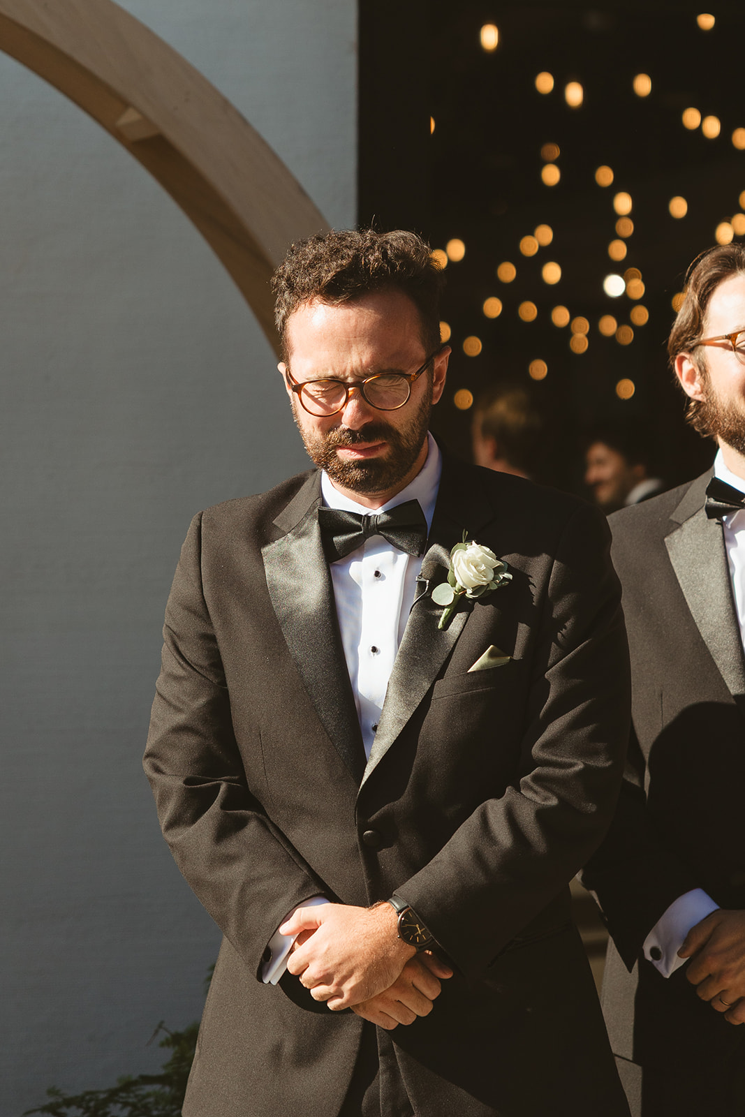 A groom crying while his bride walks down the aisle, captured through documentary style wedding photography