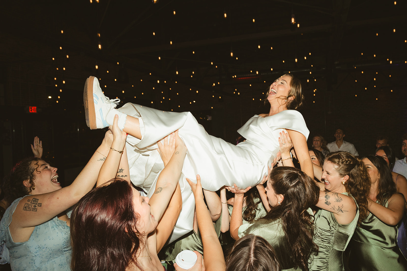 A wedding party lifting a bride in the air during a wedding reception
