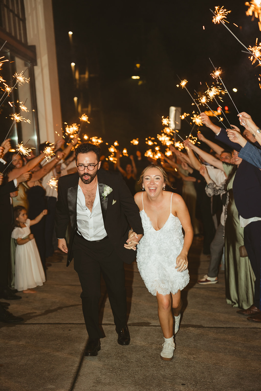 A bride and groom walking through sparklers at their wedding reception