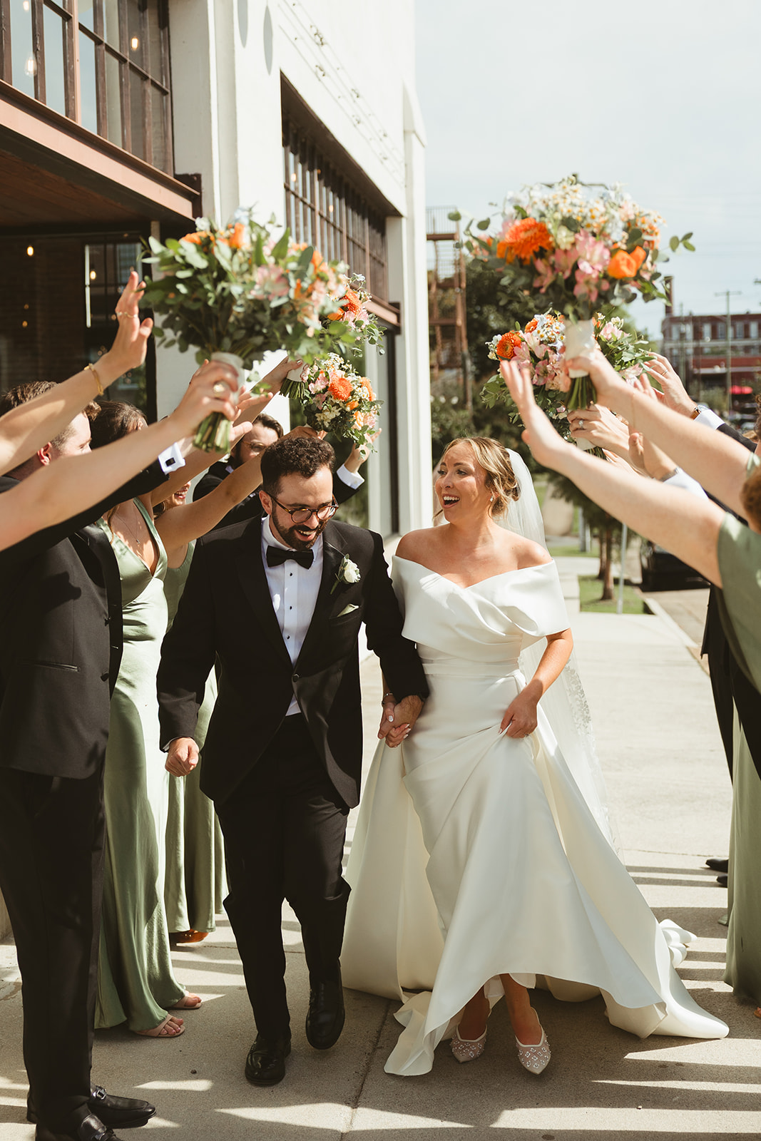 A bride and groom walking through their wedding party