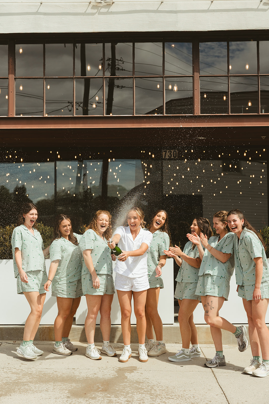 Bridesmaids and a bride popping champagne while getting ready for a wedding