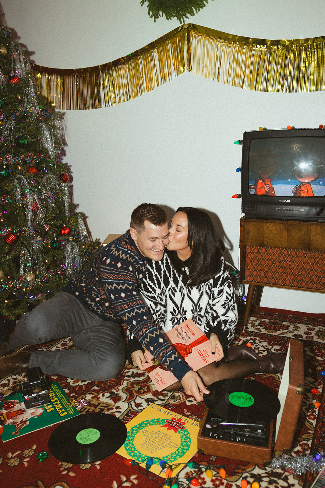 A christmas photo idea of a couple kissing while putting on a record
