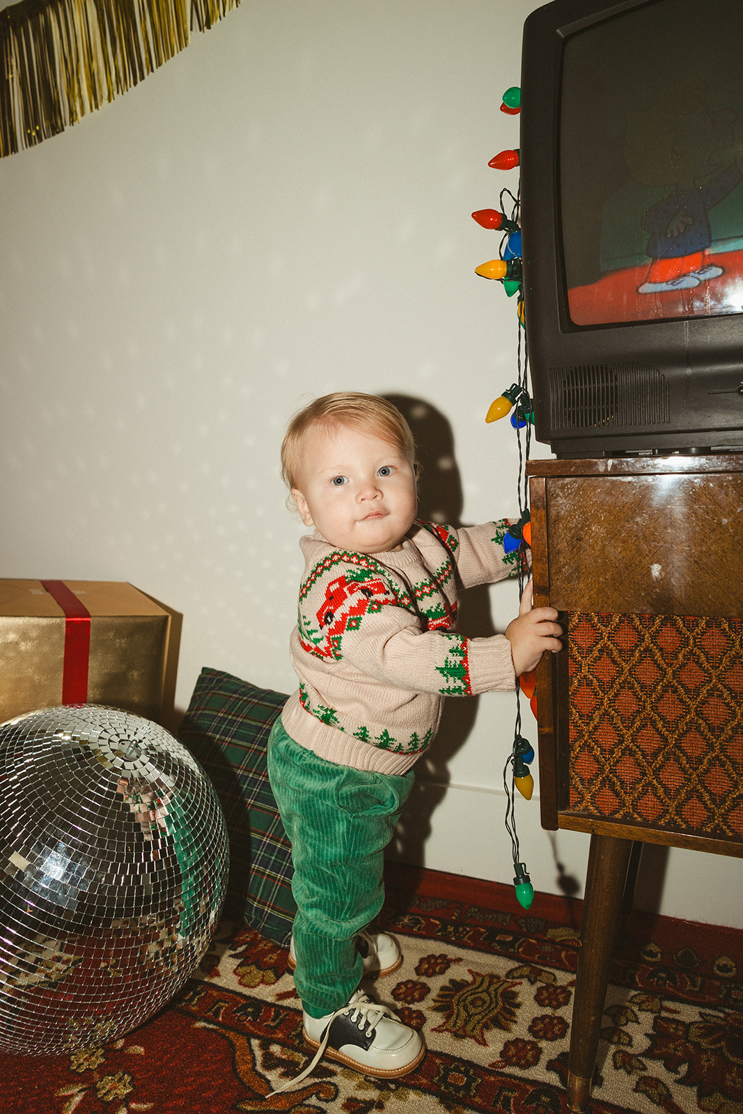 A little boy beside a disco ball and christmas lights for retro christmas pictures
