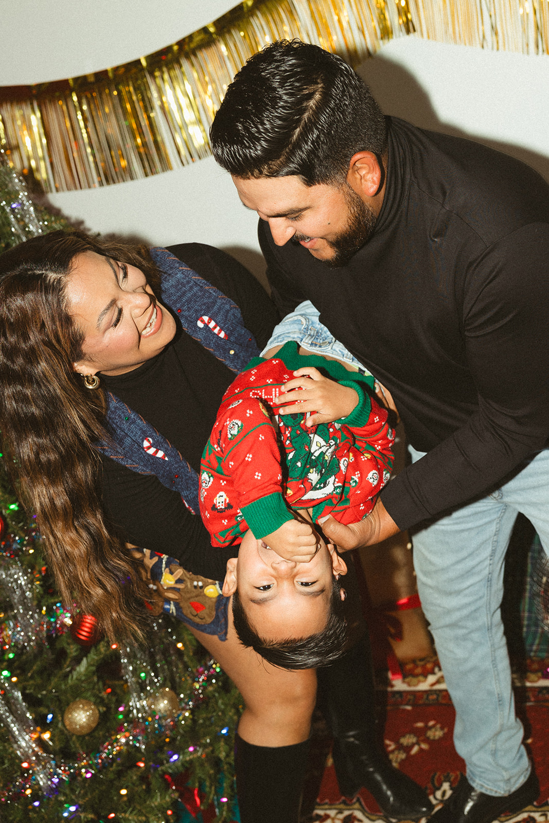 A couple holding their baby boy upside down towards the camera in retro christmas pictures