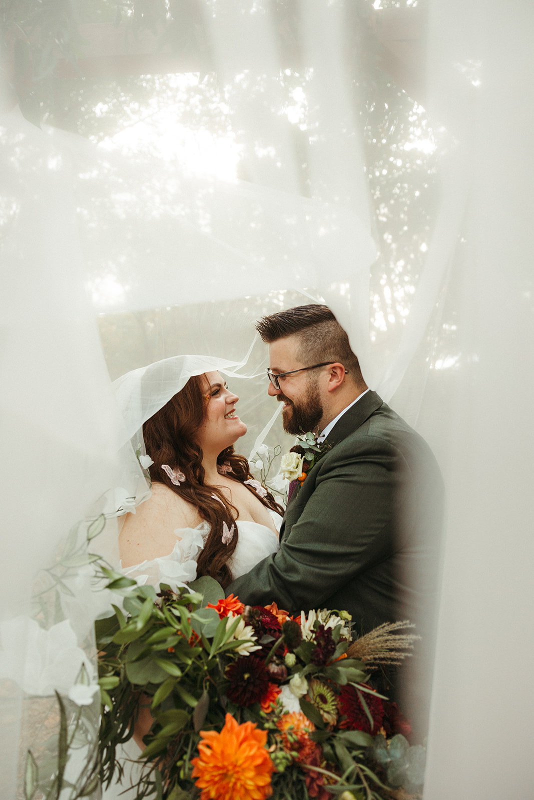 A bride and groom taking wedding photos under a veil