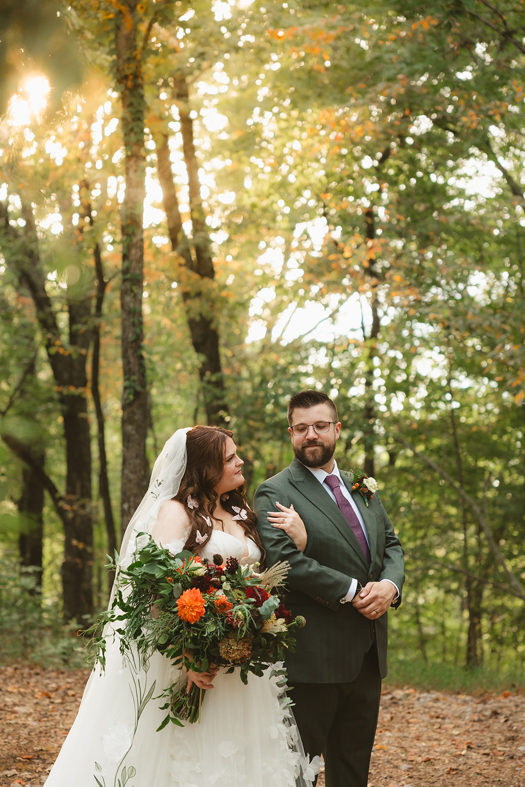 A bride and groom taking photos in the woods at Ancient Lore Village