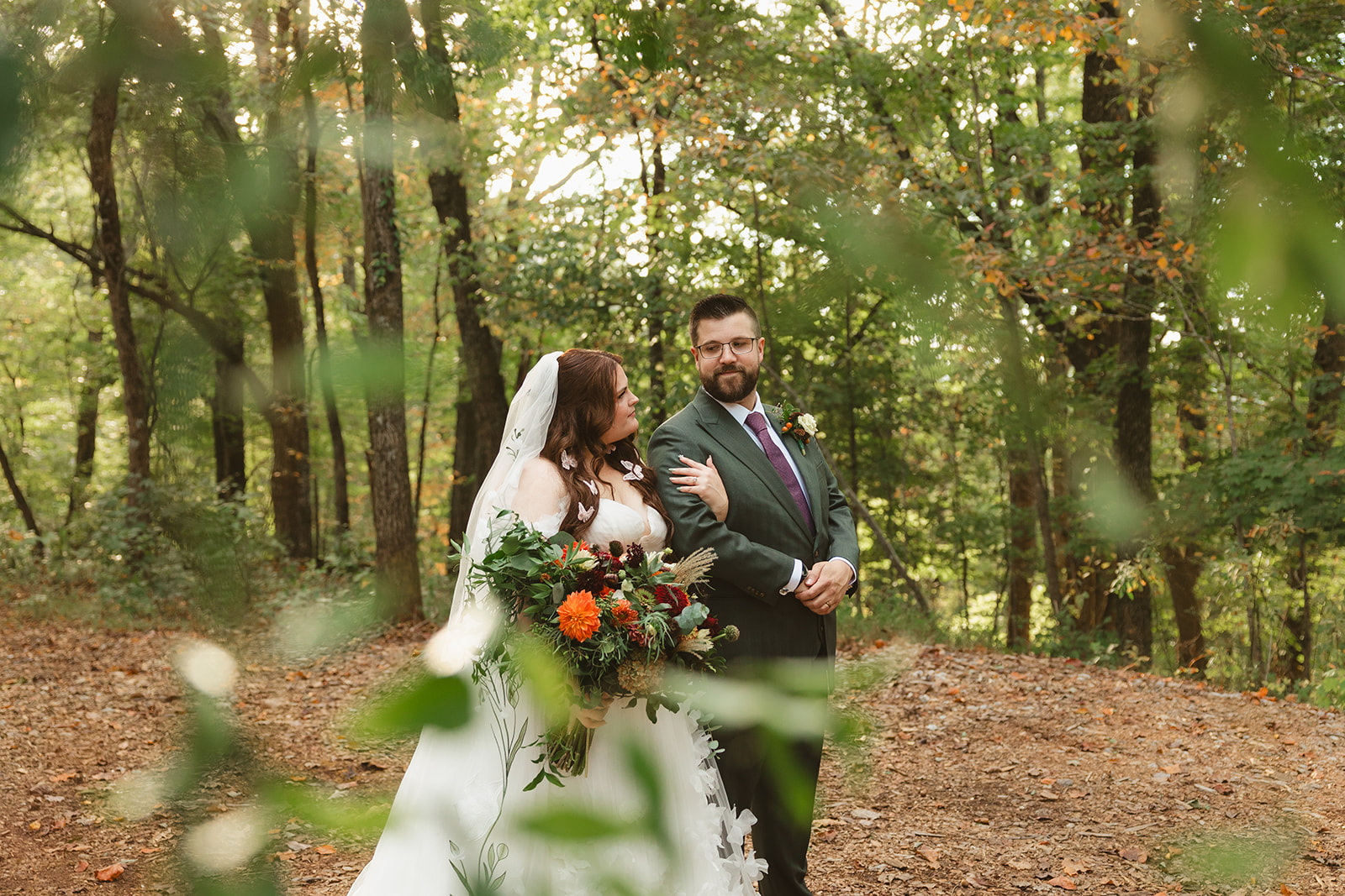 A bride and groom posing for wedding photos in the woods at Ancient Lore village
