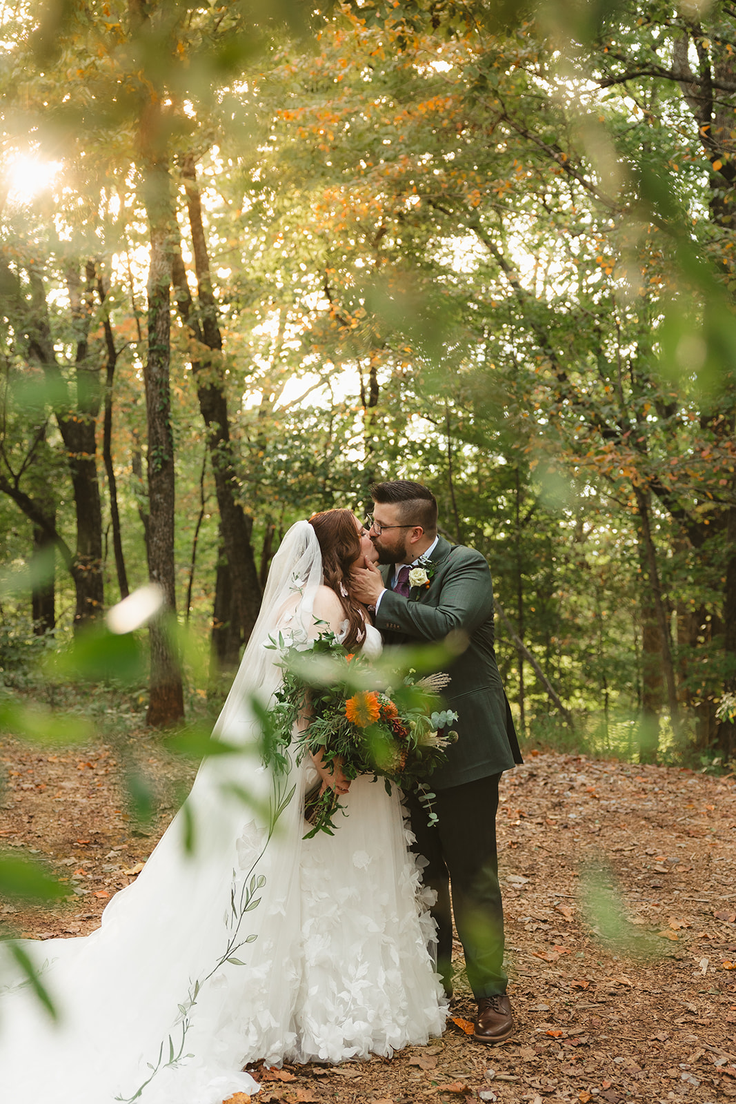 A bride and groom kissing in the woods at ancient lore village