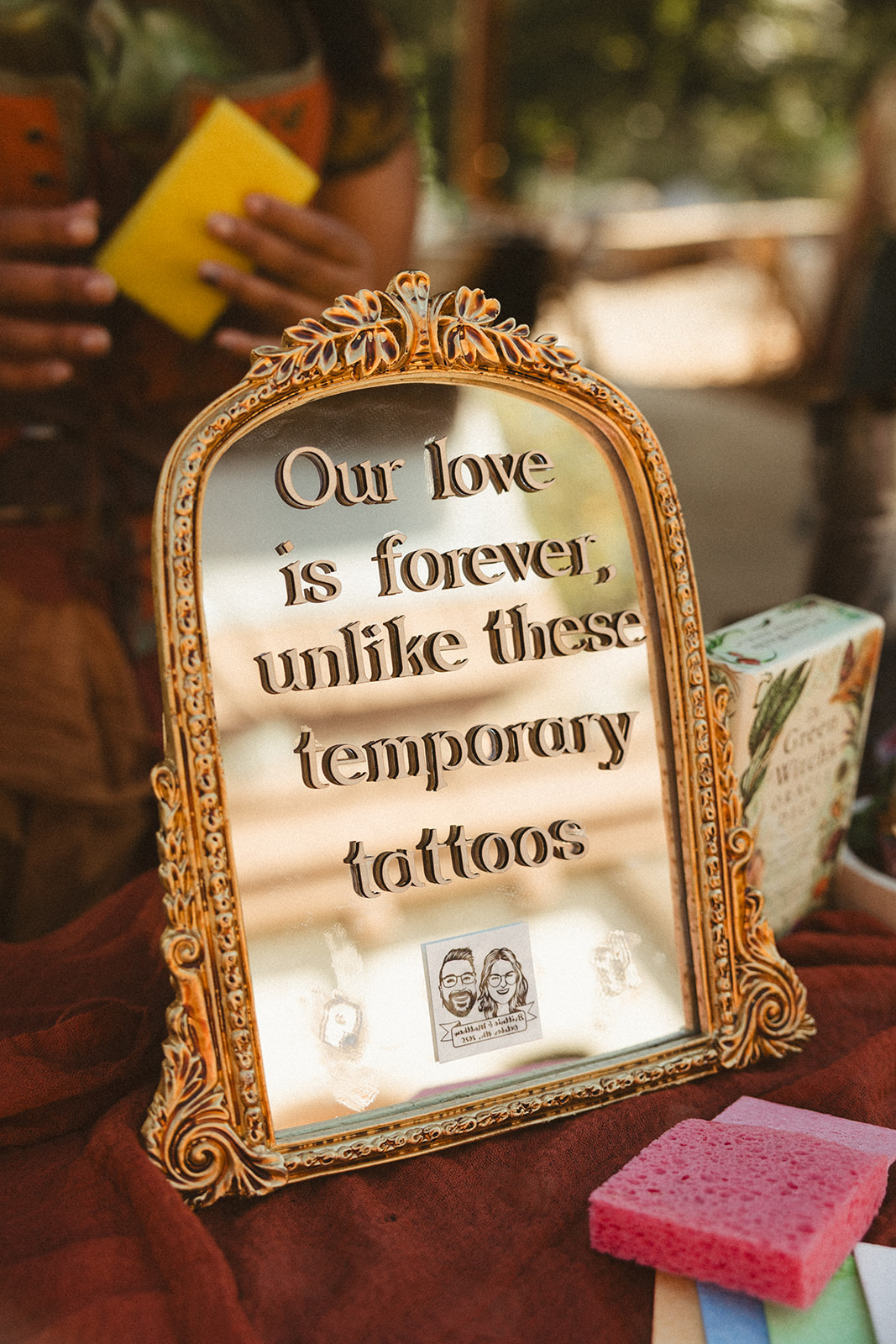 A mirror sign reading "Our love is forever, unlike these temporary tattoos" for a wedding scavenger hunt