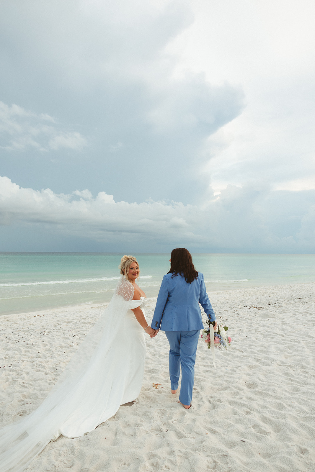 Two brides walking on the beach taking photos for their florida beach wedding