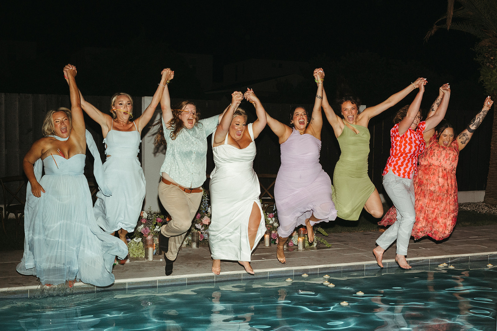 A bride and bridesmaids jumping into the pool at the end of a wedding night