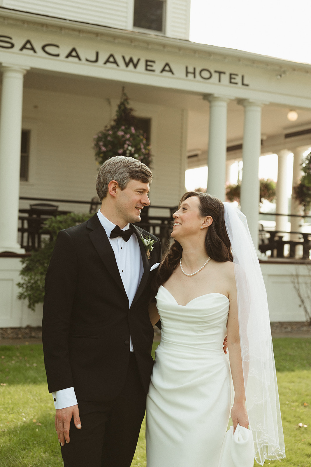A bride and groom smiling at each other in front of sacajawea hotel