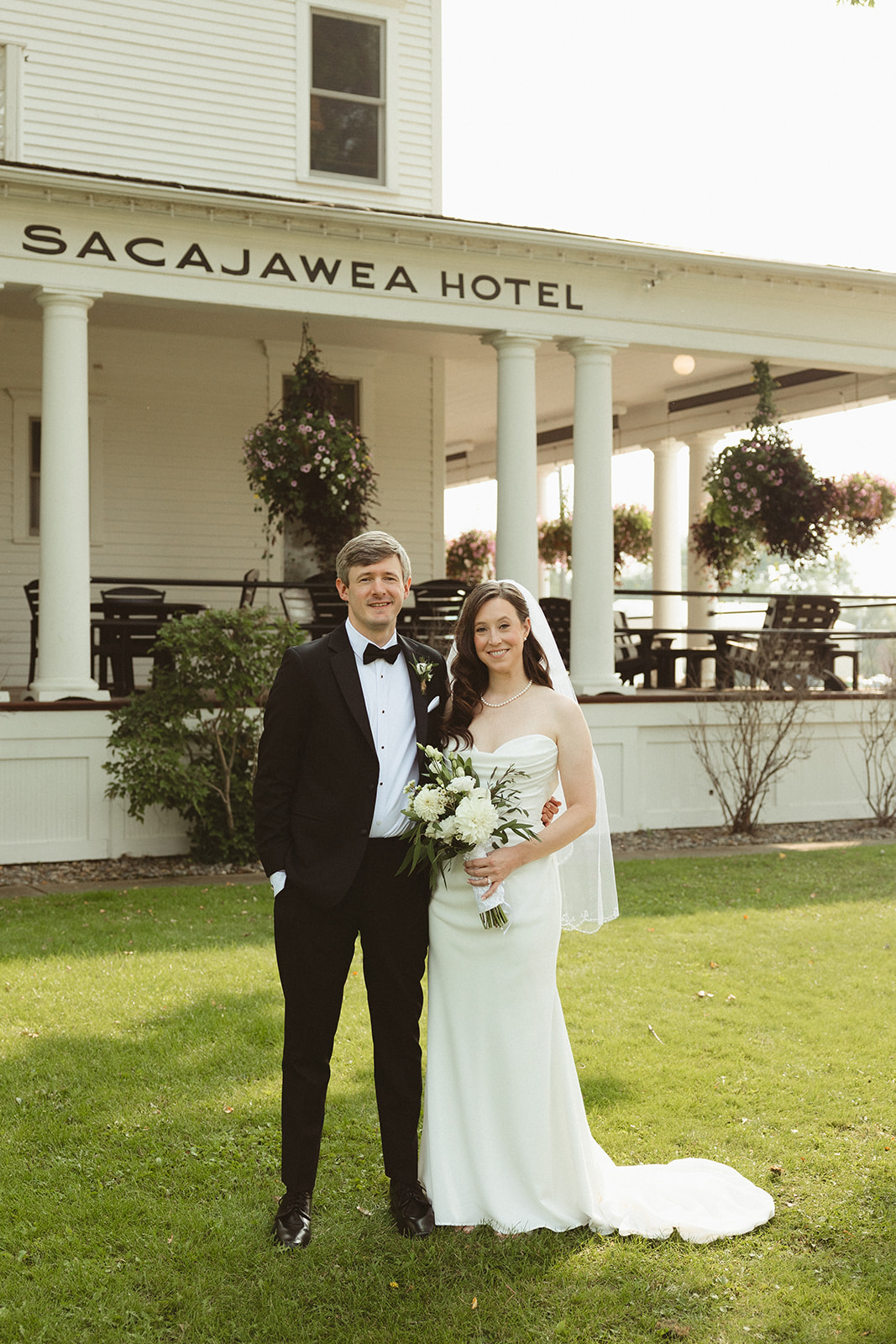 A bride and groom smiling in front of sacajawea hotel