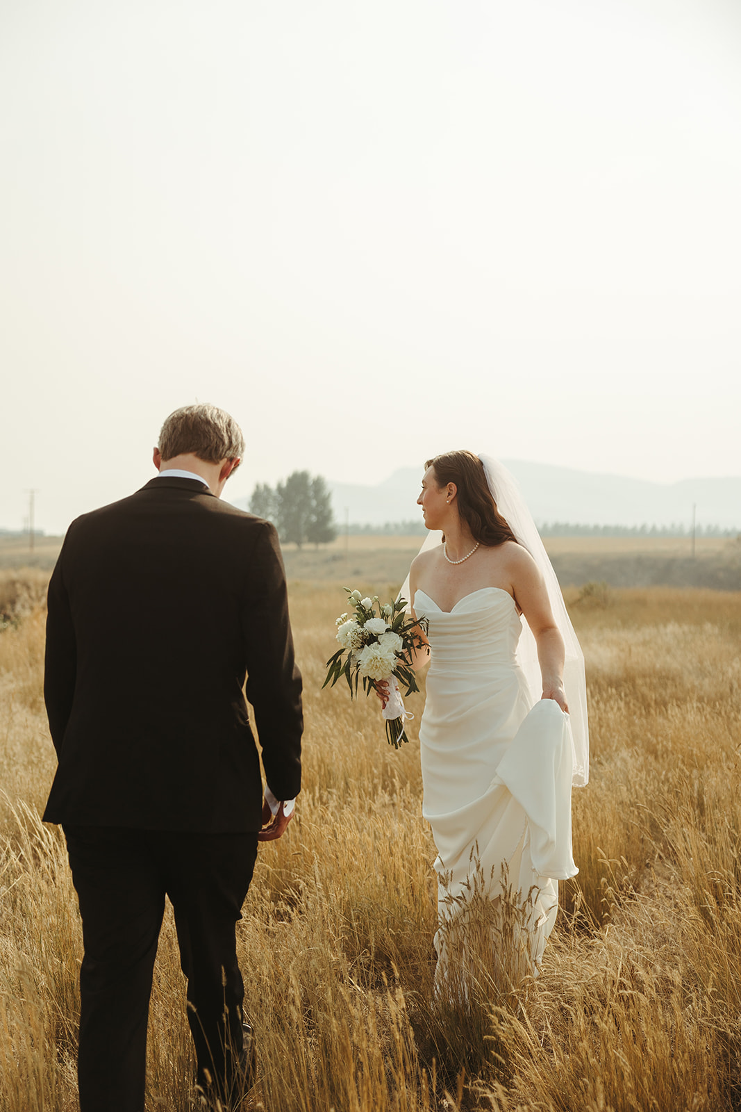 A bride and groom in a field taking wedding photos