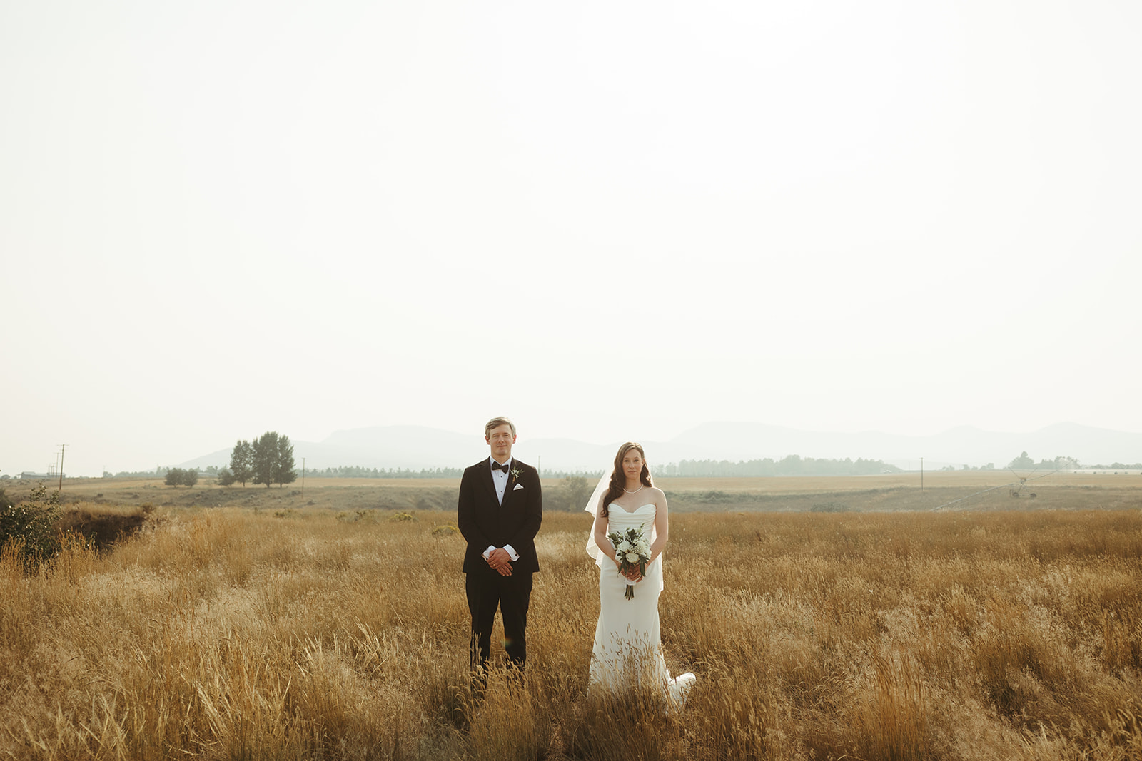 A couple posing for wedding photos in a field at Sacajawea hotel